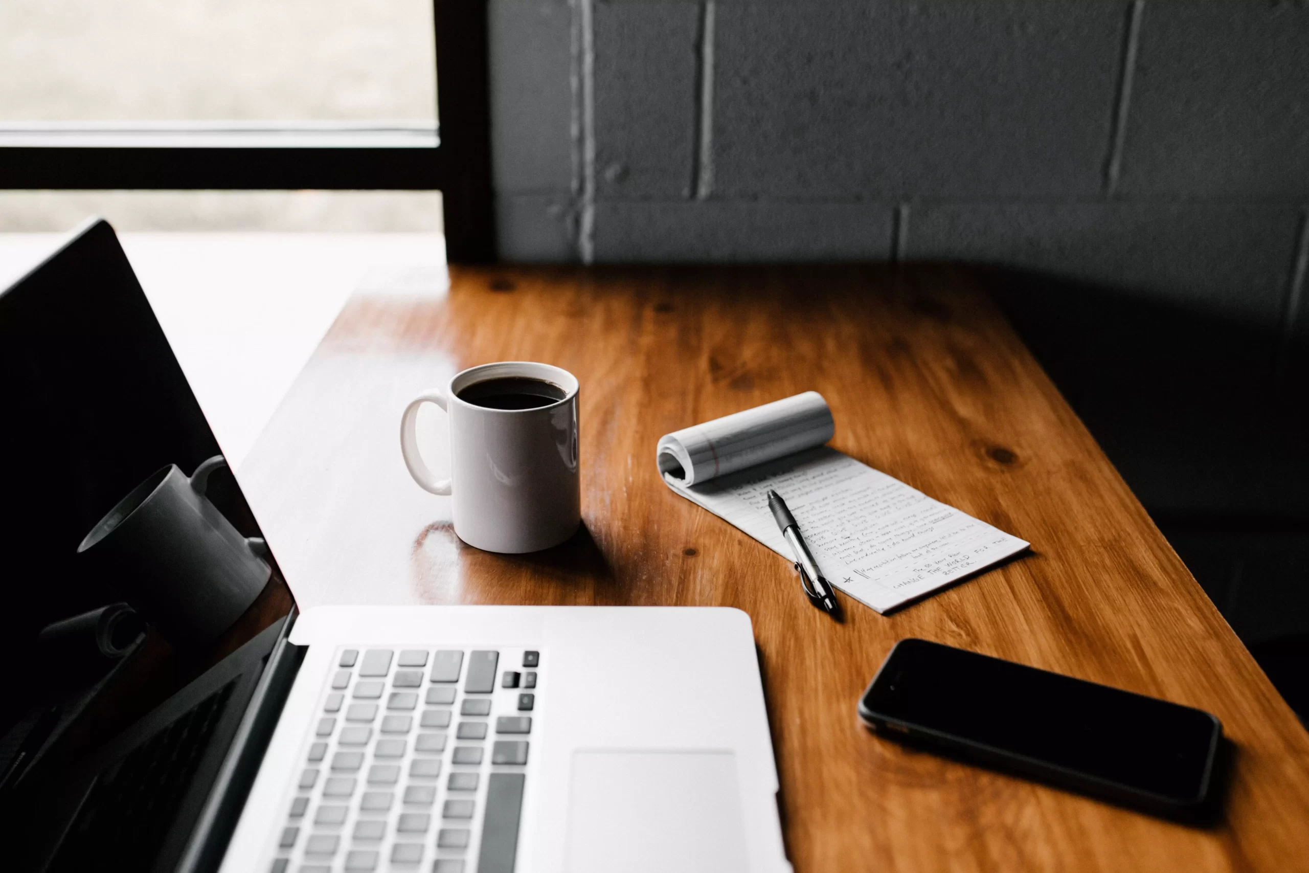 Un ordinateur et un carnet posés sur un bureau dans un espace de coworking